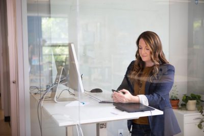 Woman at standing ergonomic adjustable desk with computer screen
